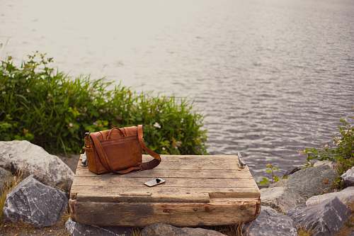 bag brown leather crossbody bag on brown wooden panel near water seattle