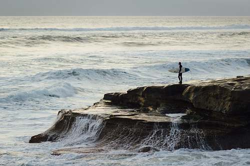 sea person carrying surfboard standing near seashore coast