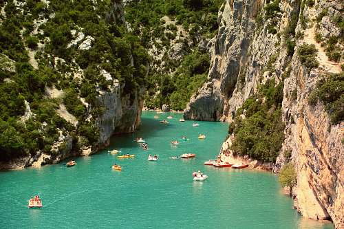 cliff yachts sailing on water between tall mountains outdoors