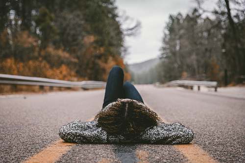 nature person lying on gray concrete road trees
