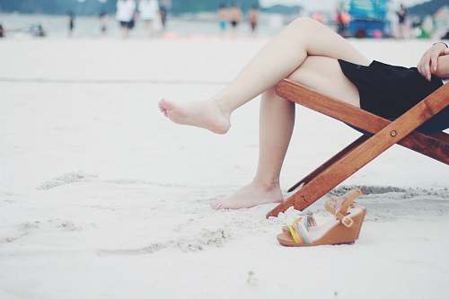 people person seats on brown folding chair during daytime beach