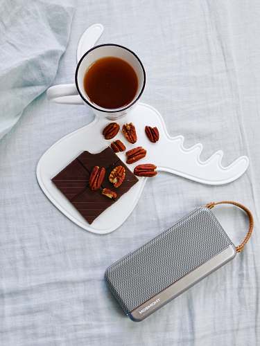 cup walnuts on white tray beside cup of coffee drink