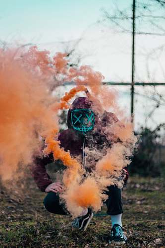 clothing person in purple hoodie releasing orange smoke smoke