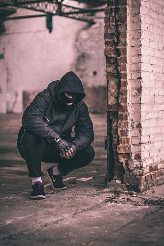 human man sitting near brick wall people
