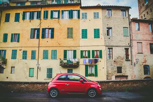 balcony red 3-door hatchback parked near the building urban