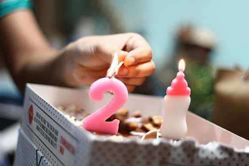 candle person lighting number 2 candle birthday cake