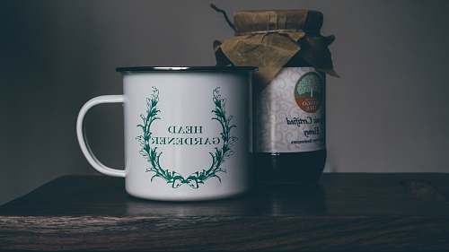 mug white head gardener ceramic cup near glass jar on brown panel jam