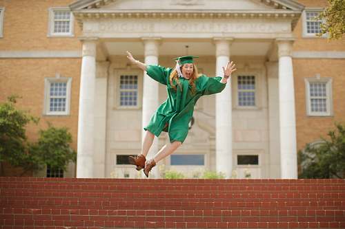 human woman wearing mortarboard jumping on staris person