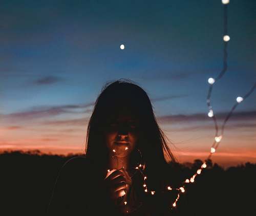 people woman holding gold string lights person