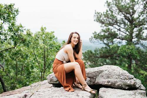 person woman sitting on gray rock sitting