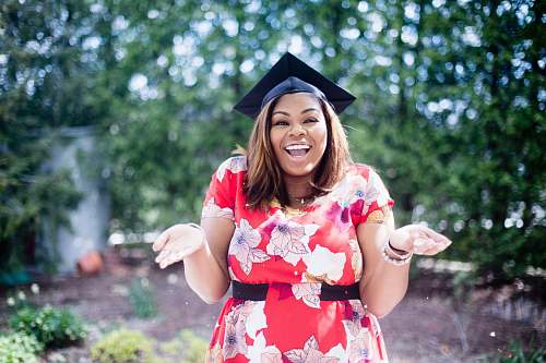 people woman wearing academic hat standing in garden showing palm at daytime woman