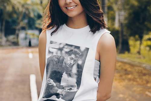 people woman wearing white sleeveless top standing on asphalt road during daytime tank top