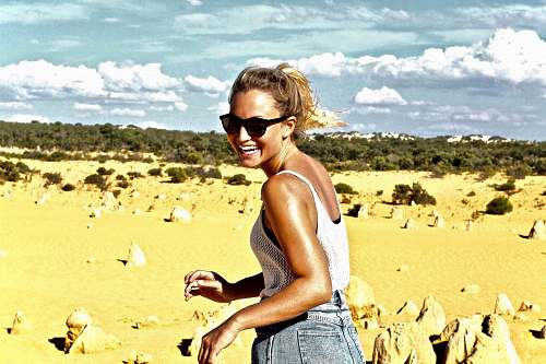 people women's in white tank top walking on brown sand during day time person