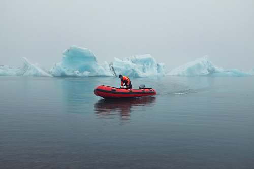 nature man riding inflatable boat near icebergs outdoors