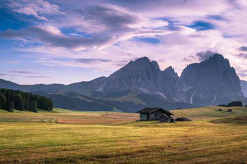 italy gray wooden house on green plains near mountain range at daytime outdoors