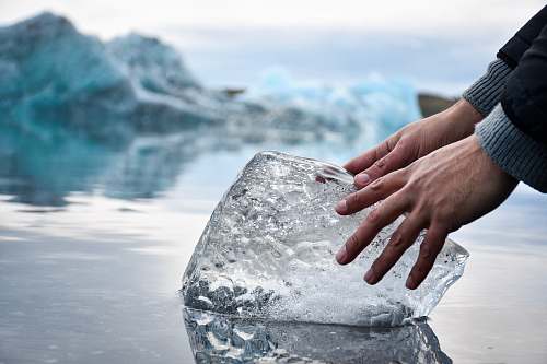 ice person with hands on ice block on water during daytime outdoors