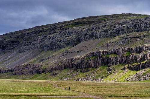 field two people standing on field near cliff landscape
