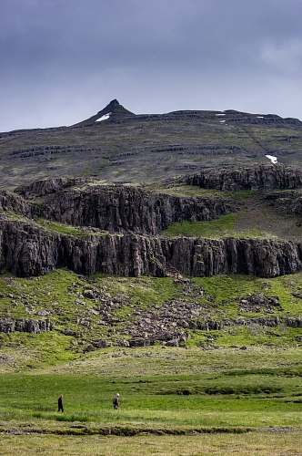 iceland two person walking on green grass field with mountain outdoors