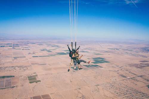 adventure two men in 1 parachute in mid air during daytime parachuting