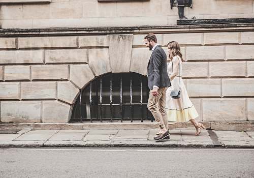 person man and woman walking beside a road during daytime human