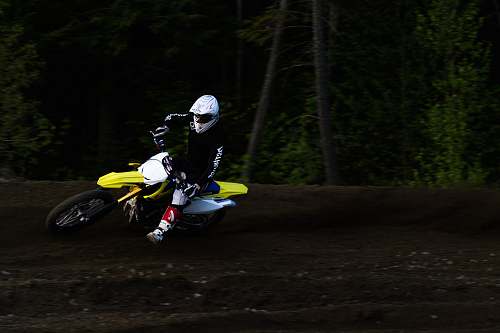 human man ridding yellow and white motocross dirt bike back