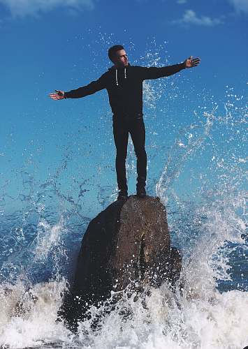 asilah man standing on rock surrounded by water morocco