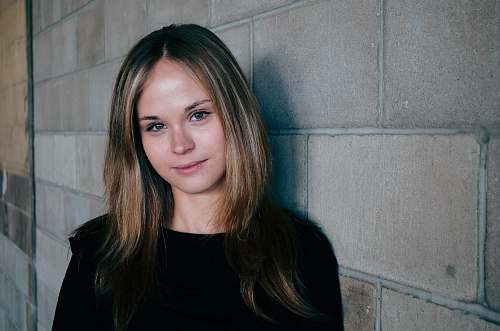 person woman leans on gray concrete wall girl