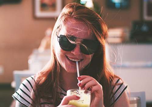 human woman sipping drink while smiling girl