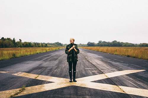 person woman standing on black asphalt between green grass under clear blue sky during daytime nashville