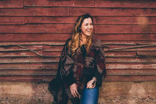 apparel smiling woman wearing brown and black poncho leaning on wall clothing