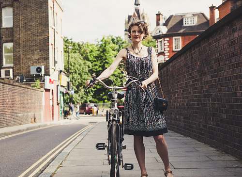 bicycle woman holding bicycle beside wall bricks bike