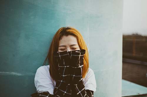woman woman leaning on wall covering her mmouth people