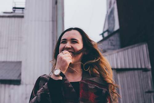 apparel woman standing while laughing and biting her finger clothing