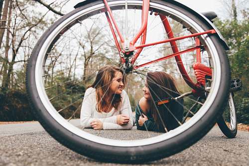 people woman wearing white scoop-neck long-sleeved shirt besides woman wearing green off-shoulder shirt on the floor bicycle