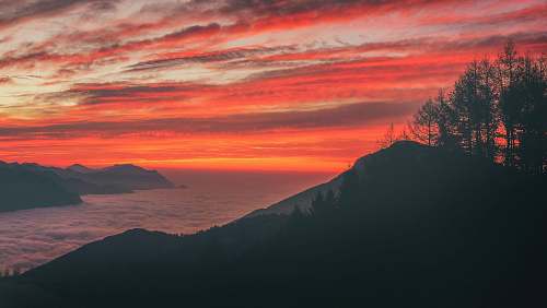 sunset silhouette photo of mountain near body of water during sunset sunrise