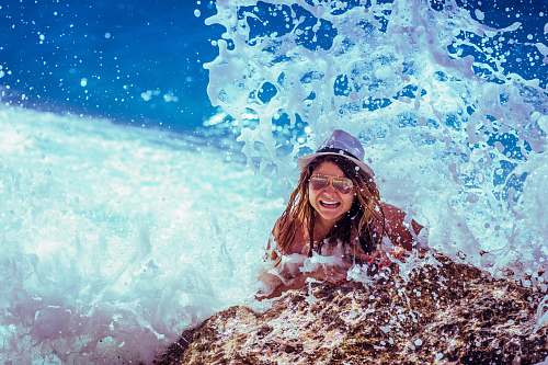 blue woman wearing white hat on top of brown rock lalaria beach