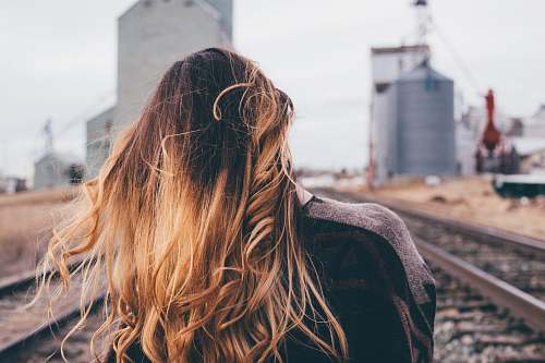 girl shallow focus photography of woman standing on train rail female