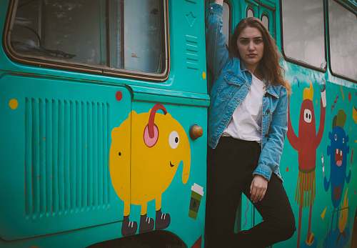  woman standing beside teal bus 