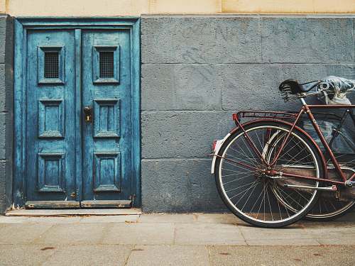 door minimalist photography of parked bicycle near blue door bike