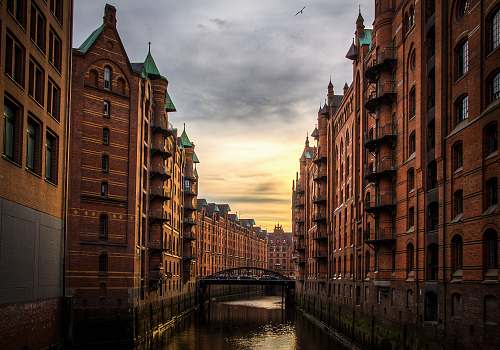 building river between brown concrete buildings canal