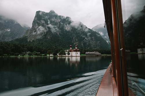 lake brown wooden boat on body of water in front of mountain photo fog