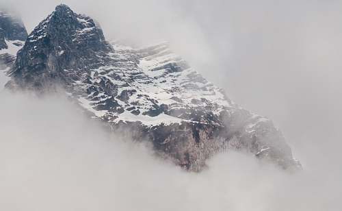 grey snowy mountain covered by fog mountain