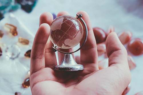 glass person holding gray metal framed desk globe paper weight prism