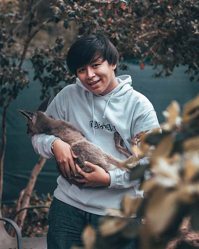 human man in grey hoodie clutching grey animal person