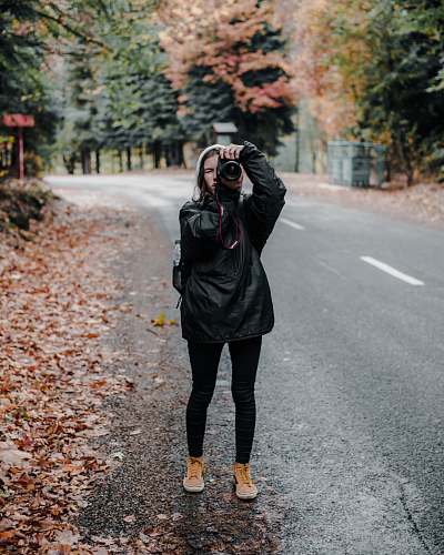 clothing man holding camera standing on road footwear