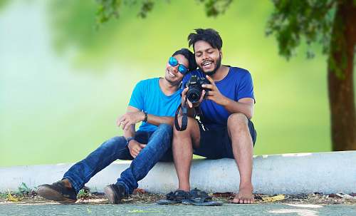 clothing smiling man leaning on shoulder of another man while sitting footwear