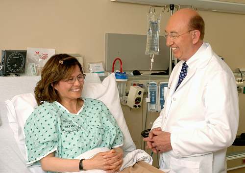 human woman in teal scrub suit sitting beside man in white medical scrub suit person