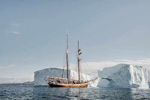 transportation brown boat near ice berg during daytime vehicle
