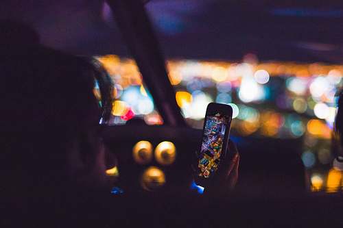 lights person using Android smartphone inside car aerial view