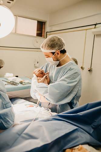 hospital man in lab suit and mask carrying newborn baby human